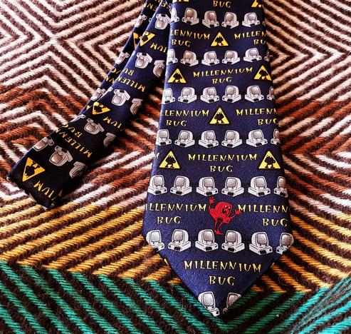 A blue neck tie with lots of small computers, bugs and text saying Millennium Bug
